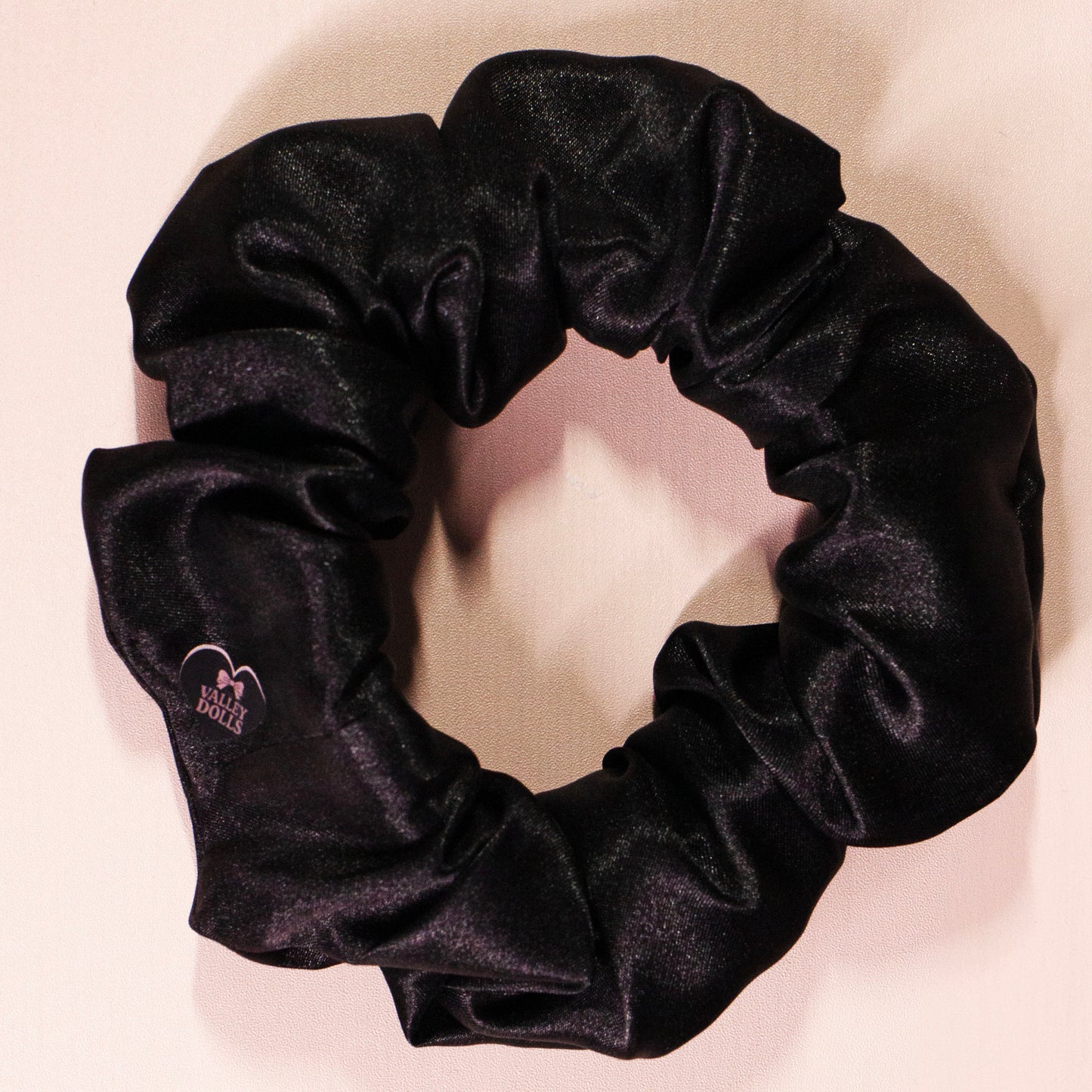 Black satin scrunchie with a subtle shine, handmade hair accessory photographed on a light neutral background