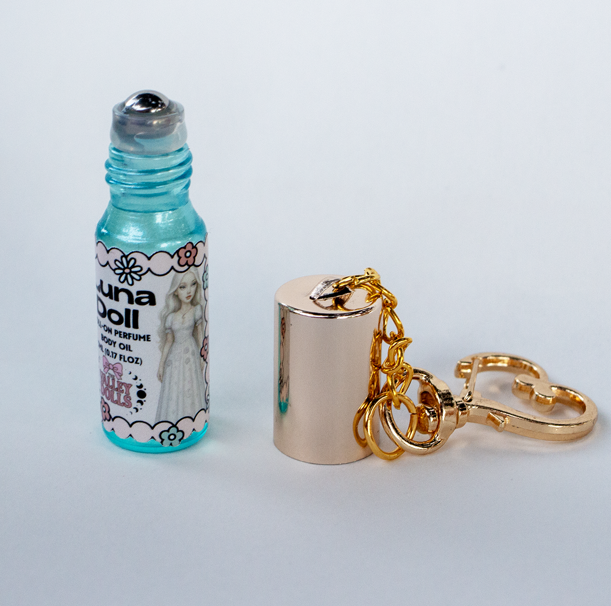 Luna Doll perfume oil roll-on in a 5 ml glass bottle with gold keychain clasp and cap removed – The Valley Dolls fragrance.
