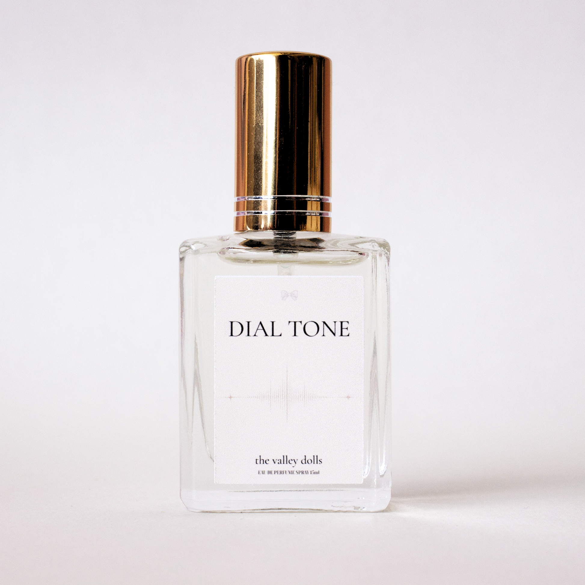 Luxury perfume bottle labeled “Dial Tone” with gold cap and minimalist white label on a white background