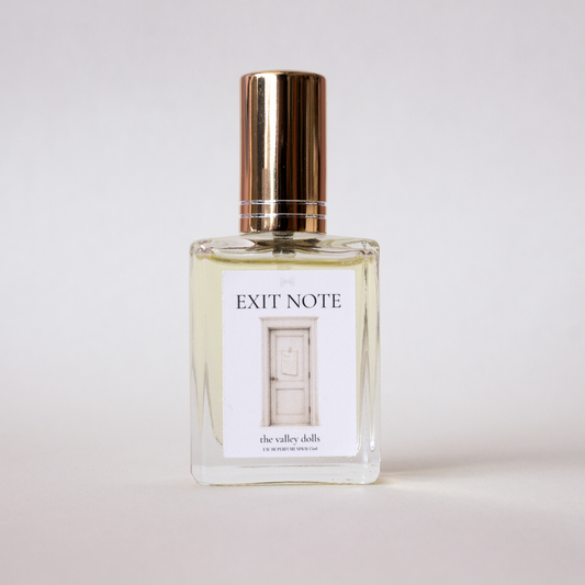 Luxury perfume bottle labeled “Exit Note” with gold cap and minimalist label on a white background