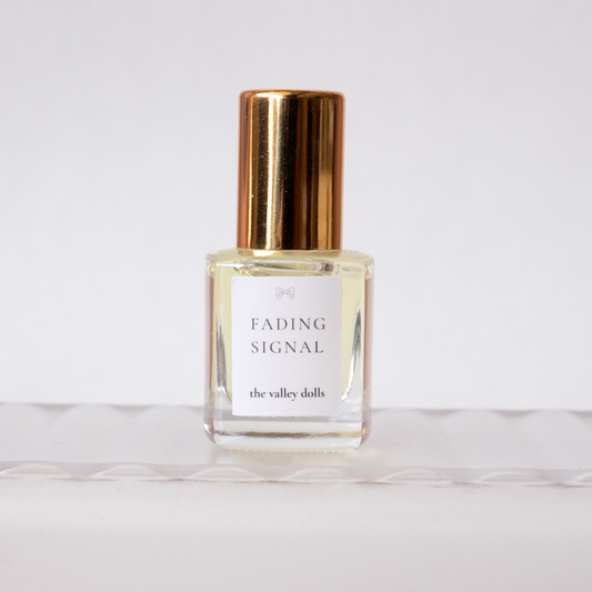 Luxury perfume oil bottle labeled “Fading Signal” with gold cap on a white background