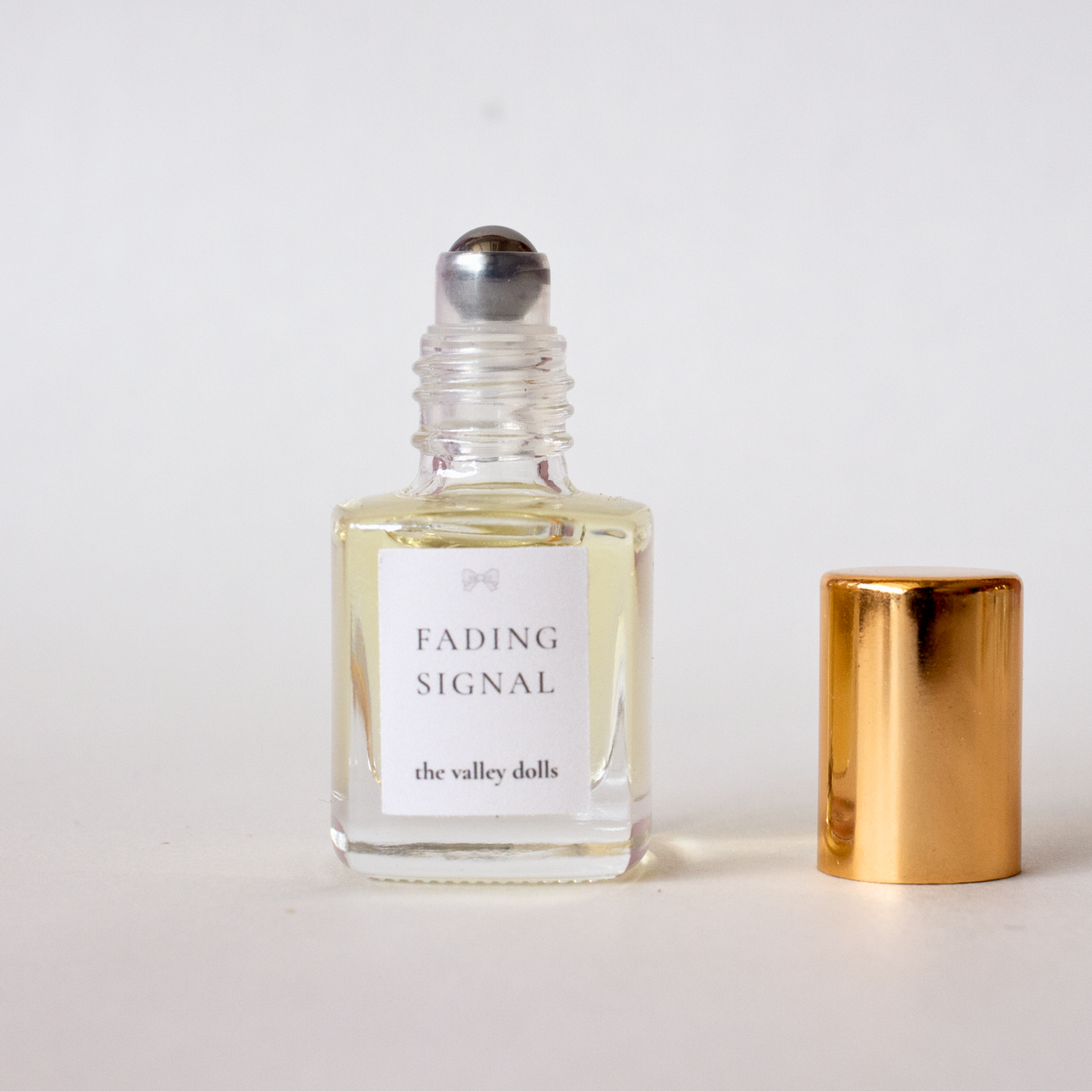 Open luxury perfume oil bottle labeled “Fading Signal” with exposed roller applicator on a white background