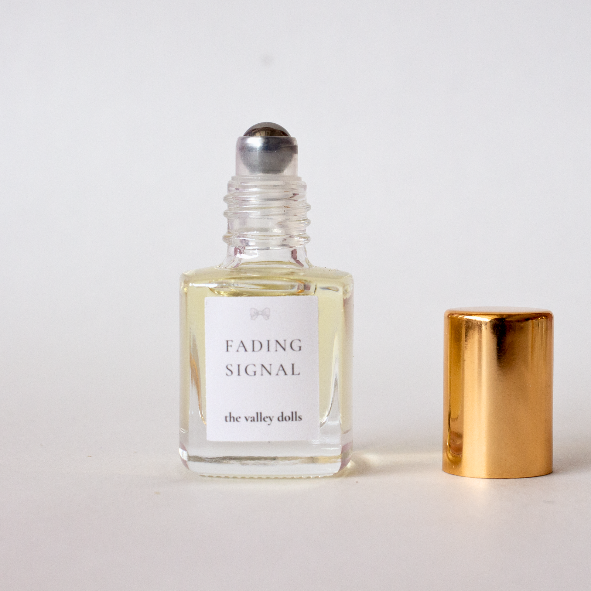 Open luxury perfume oil bottle labeled “Fading Signal” with exposed roller applicator on a white background