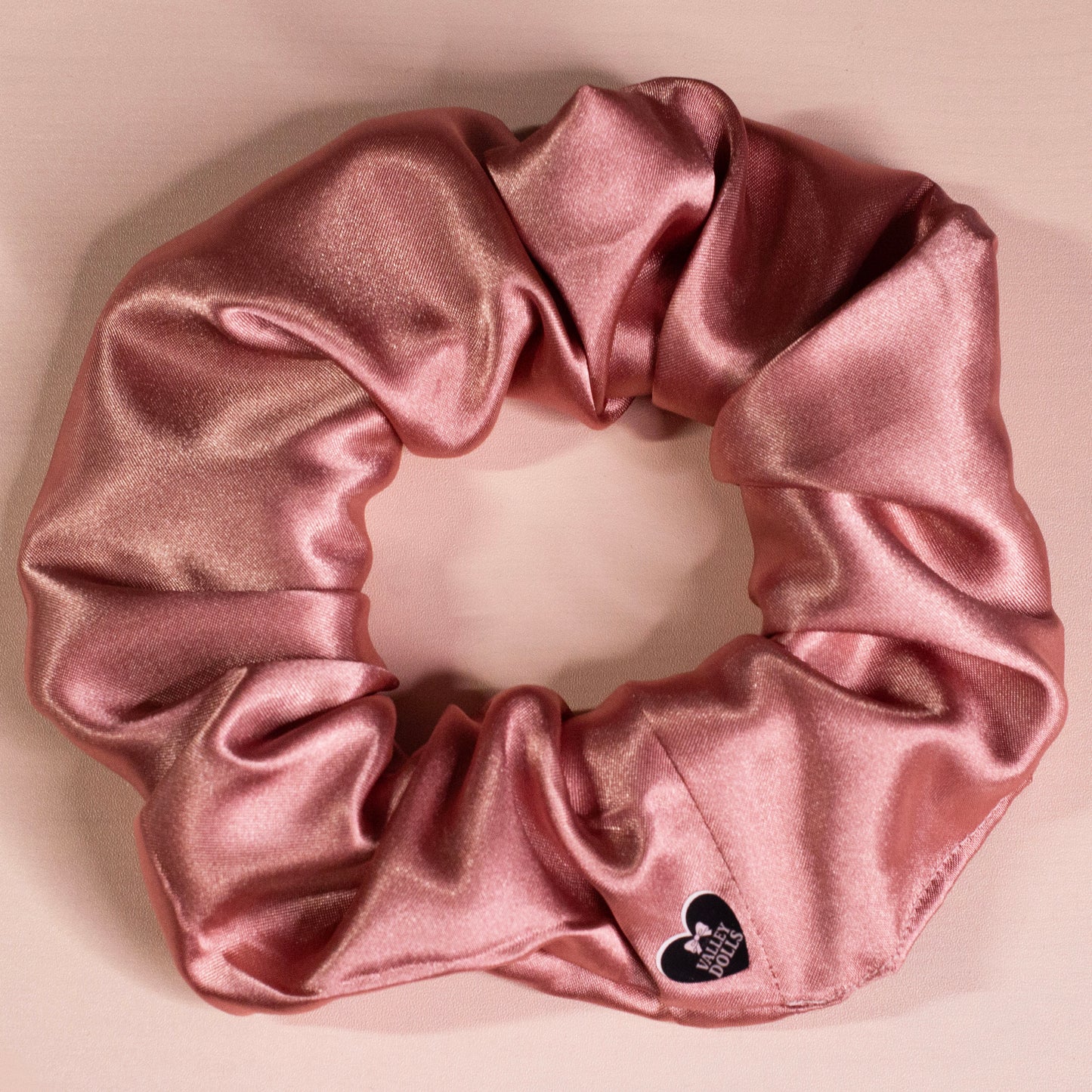 Mauve satin scrunchie with a soft sheen, handmade hair accessory photographed on a neutral beige background
