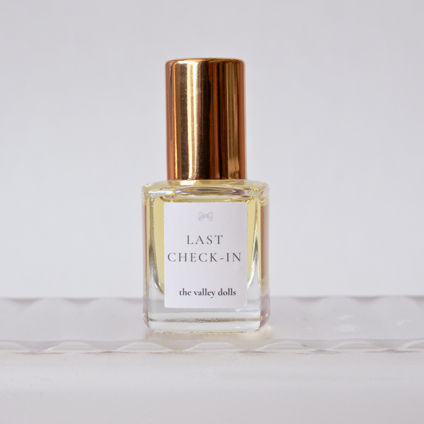 Luxury perfume oil bottle labeled “Last Check-In” with gold cap on a white background
