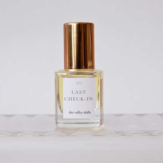 Luxury perfume oil bottle labeled “Last Check-In” with gold cap on a white background