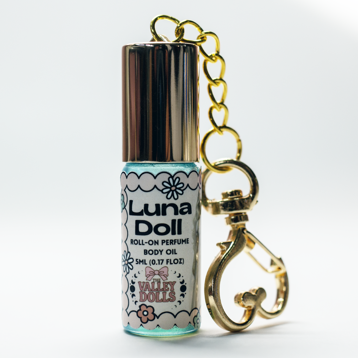 Luna Doll perfume oil roll-on keychain bottle, angled view with gold clasp and label