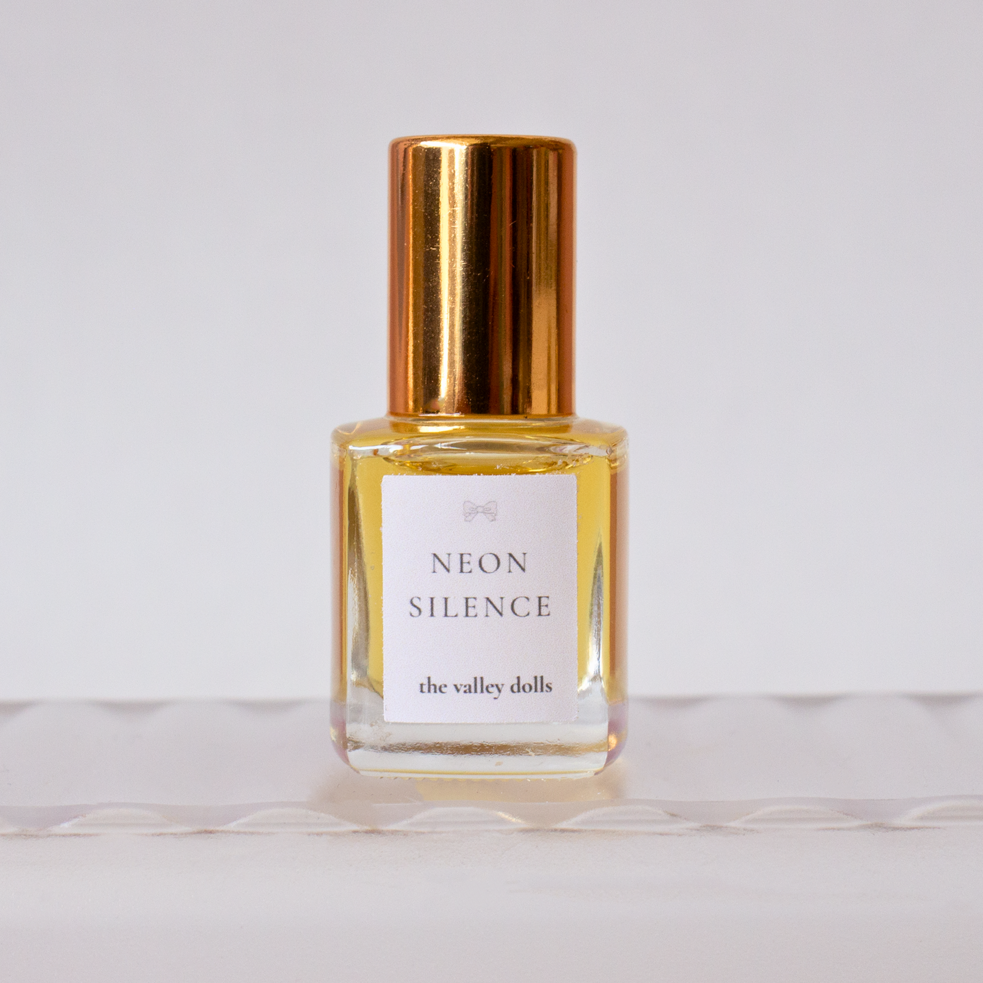 Luxury perfume oil bottle labeled “Neon Silence” with gold cap on a white background