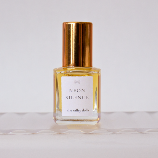 Luxury perfume oil bottle labeled “Neon Silence” with gold cap on a white background