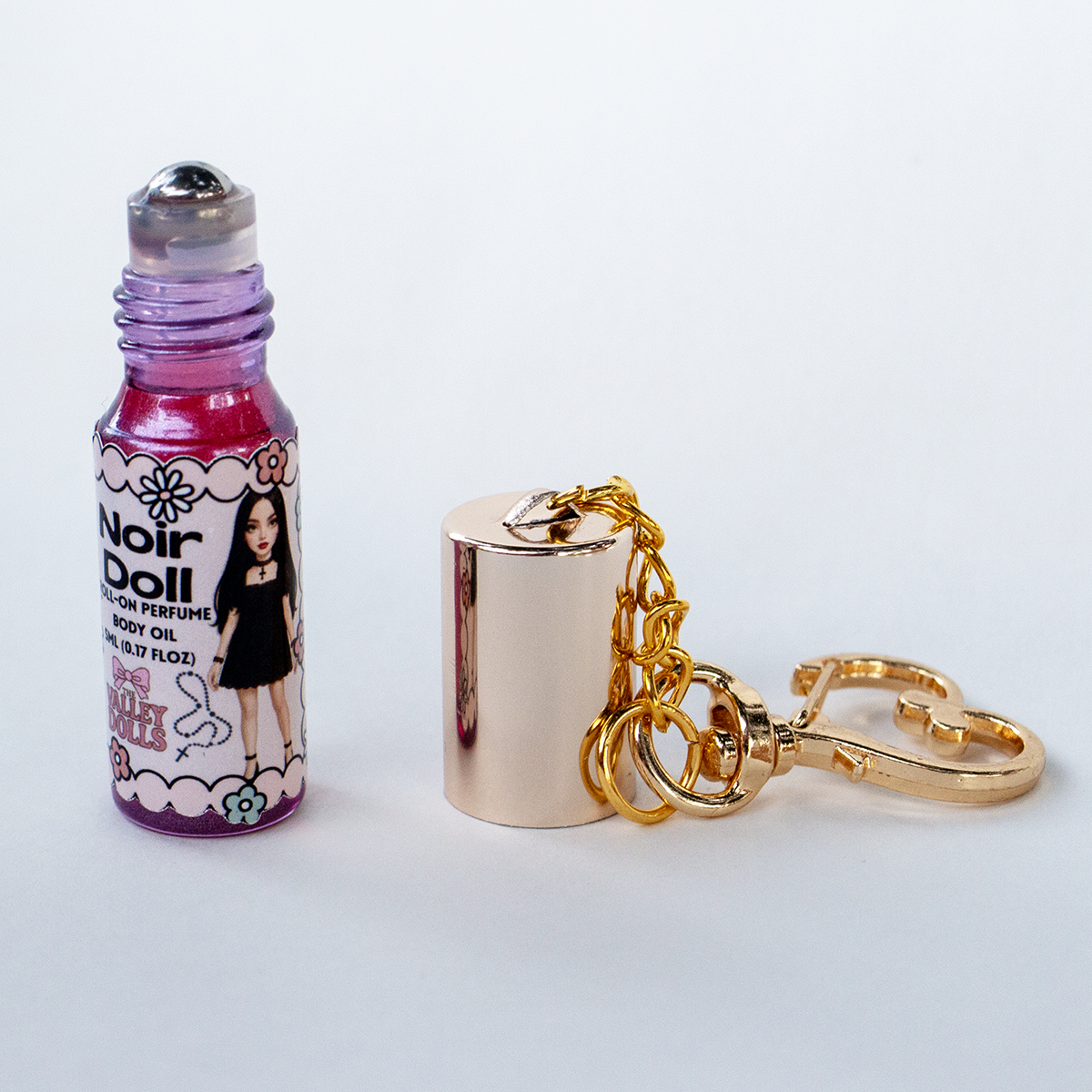 Noir Doll perfume oil roll-on, 5 ml glass bottle with rollerball applicator and gold heart keychain clasp – smoky sweet fragrance from The Valley Dolls