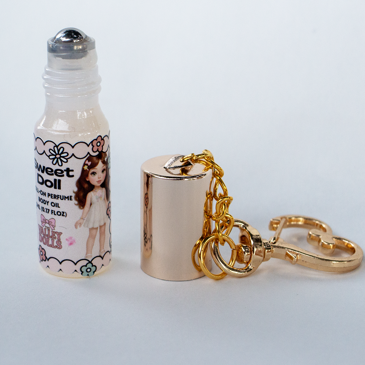 Sweet Doll perfume oil roll-on bottle open, rollerball applicator shown with gold heart keychain clasp – 5 ml travel size fragrance from The Valley Dolls