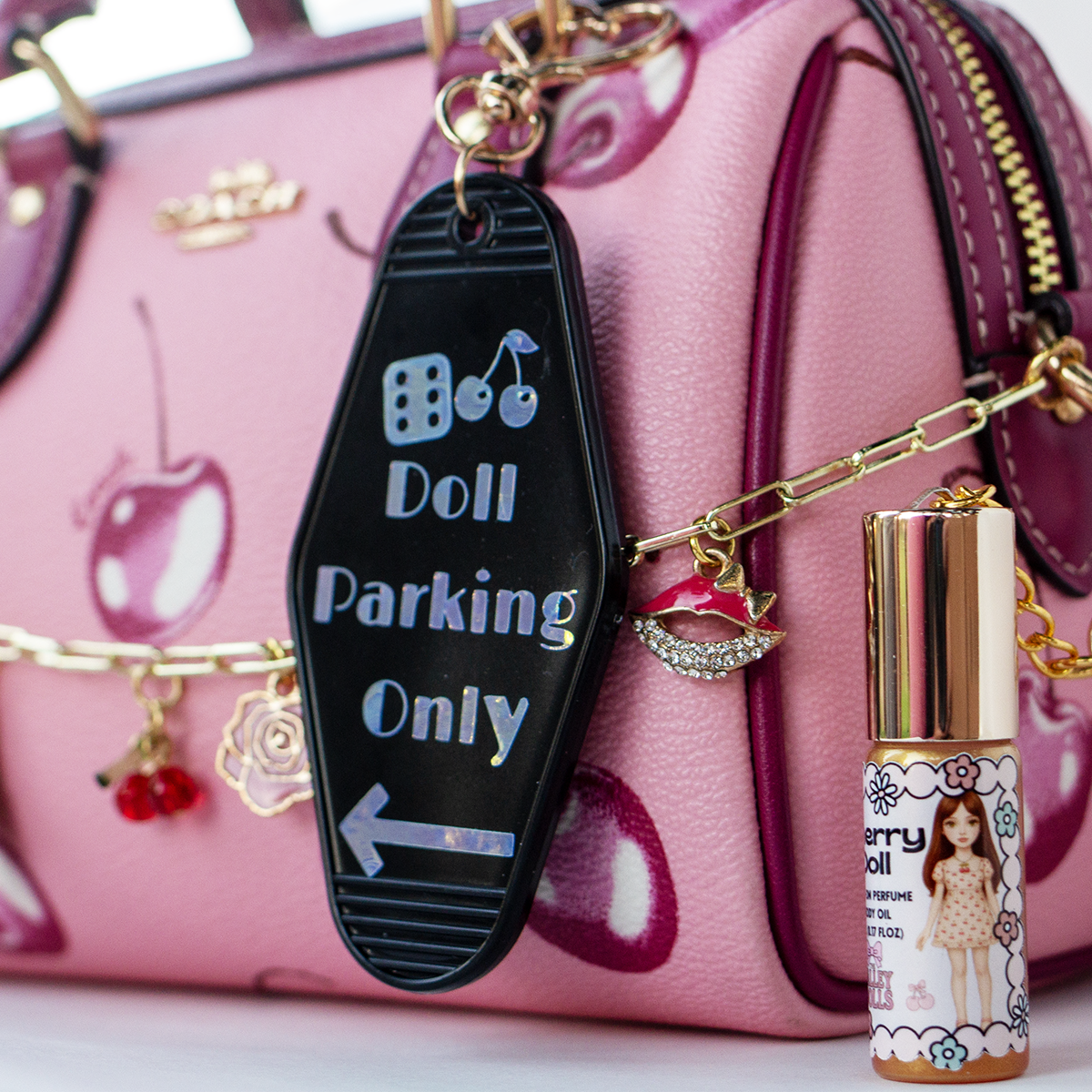 The Valley Dolls Doll Parking Only motel keychain on pink cherry purse with Cherry Doll perfume oil bottle