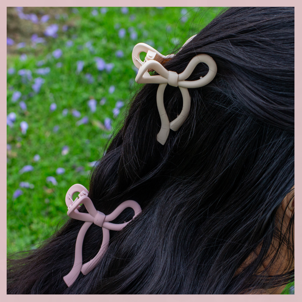Beige and mauve bow hair clips in dark hair, The Valley Dolls accessories, outdoor grass background
