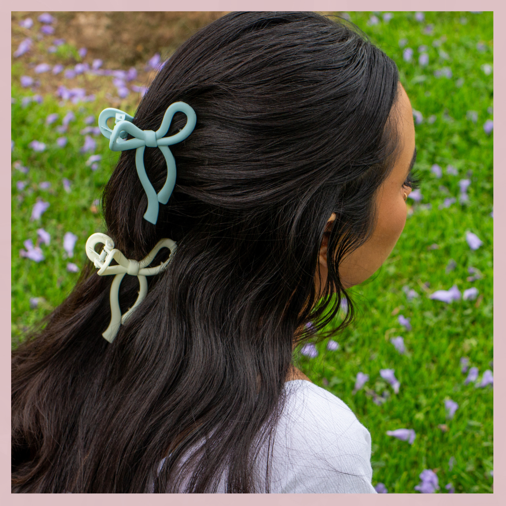 Blue and soft yellow bow hair clips in dark hair, The Valley Dolls accessories, outdoor grass background