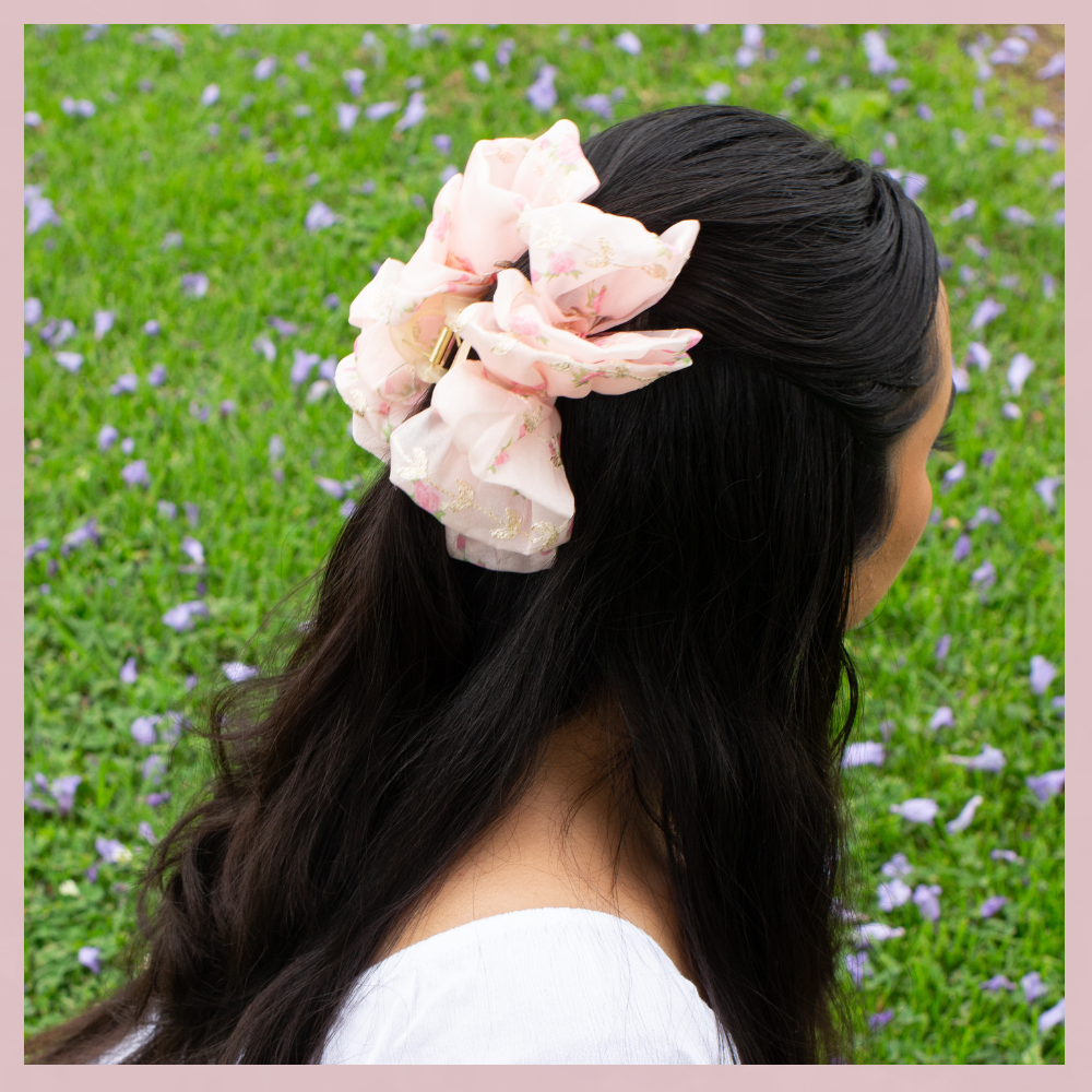 Soft pink floral mesh hair bow clip in dark hair, The Valley Dolls accessory, outdoor grass background